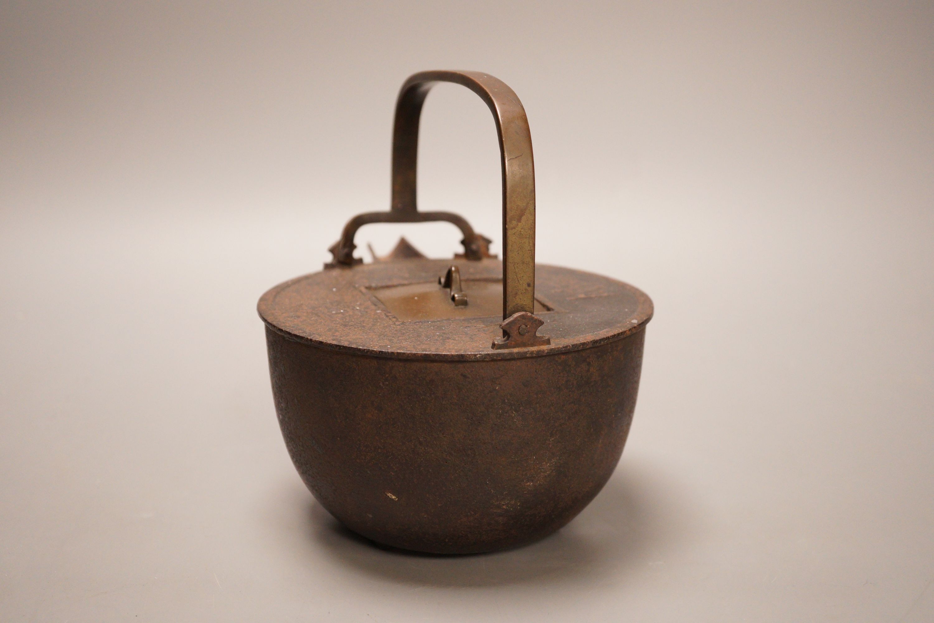 A Japanese cast iron and bronze teapot on tripod stand, inscribed, 19cm wide including spout